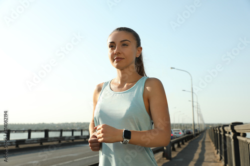 Woman wearing modern smart watch during training outdoors © New Africa