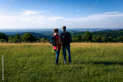 Active senior couple with backpacks hiking in nature.