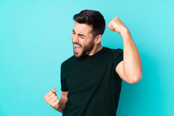 Caucasian handsome man isolated on blue background celebrating a victory