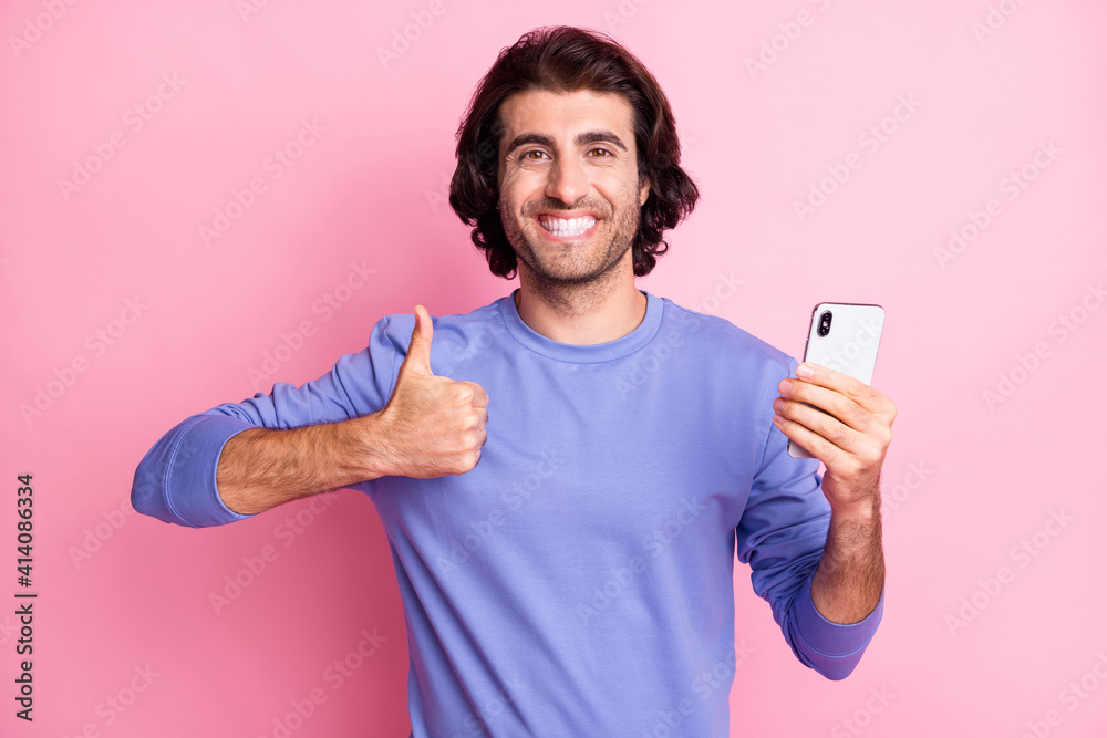 Portrait of funky guy hold telephone show approve sign blink wear purple sweater isolated on pastel pink color background Portrait of funky guy hold telephone show approve sign blink wear purple sweater isolated on pastel pink color background