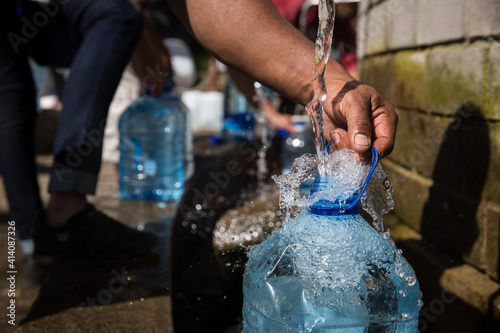 Person collecting water in plastic bottle is drought in Cape Town South Africa