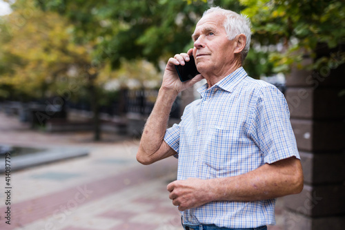 elderly european man talking on the phone in summer park