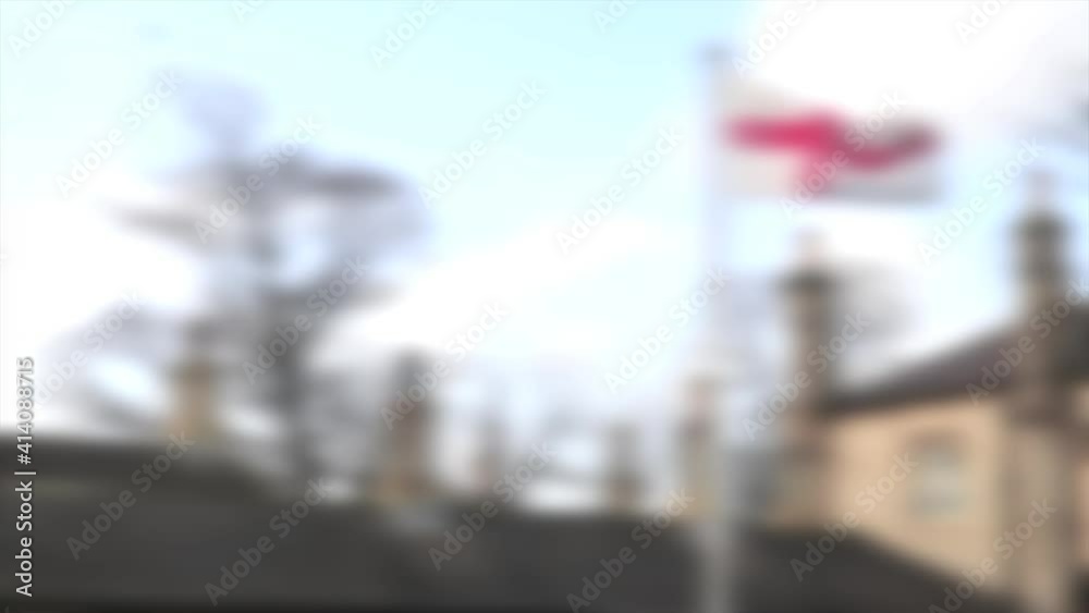 Abstract blurred St Georges Flag for England flying on a flagpole over the top of rooftops with chimney stacks Abstract blurred St Georges Flag for England flying on a flagpole over the top of rooftops with chimney stacks