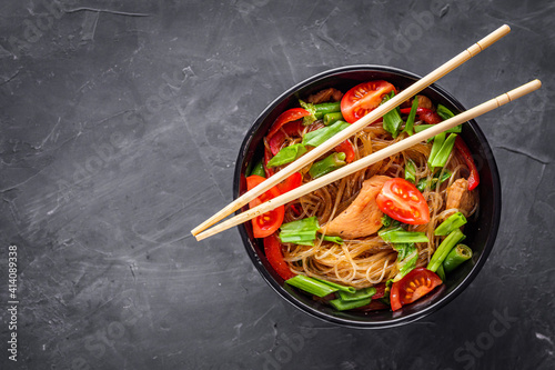 delicious glass noodles with chicken and vegetables on a dark stone background