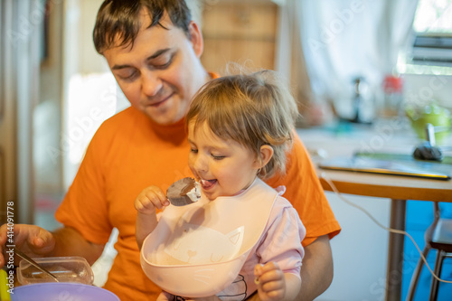 little cute toddler girl eating ice cream popsicle sitting on daddy's lap