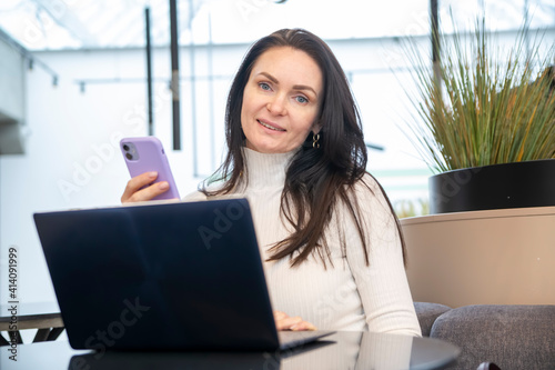 young woman works on laptop and smartphone in cafe. Free Download young woman works on laptop and smartphone in cafe. - GFXLoad
