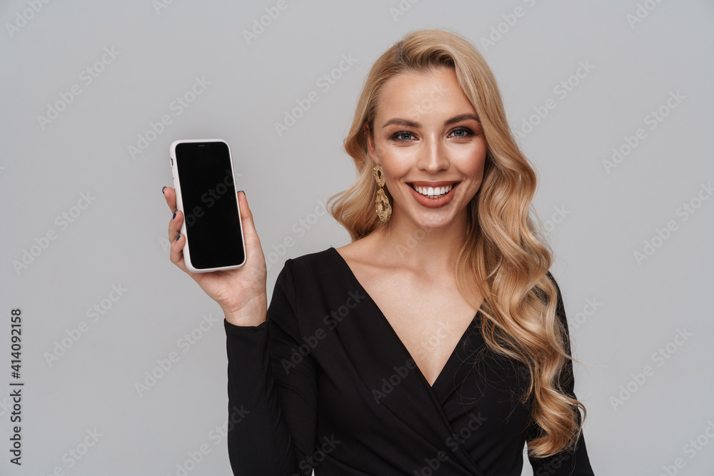 Happy girl in luxury earrings smiling while showing mobile phone Happy girl in luxury earrings smiling while showing mobile phone