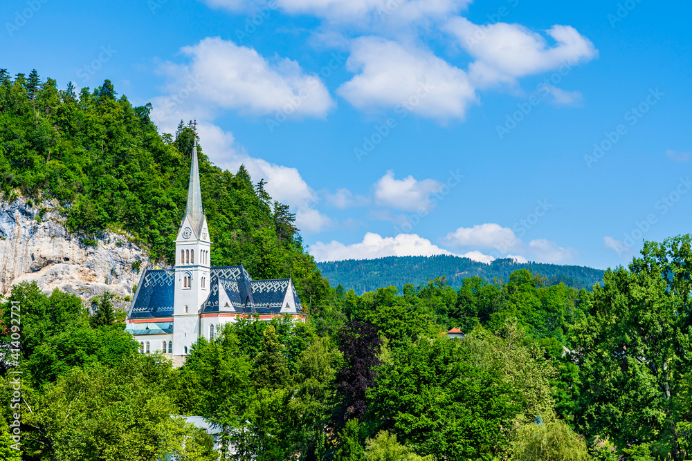 St. Martin church in Bled, Slovenia. Small white church surrounded by green trees on top of a rock hill
