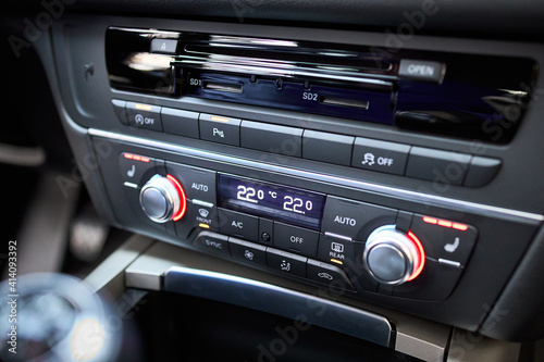 Modern car climate control panel for driver and passenger with shallow depth of field. Zone climate control. Car interior detail. Multimedia radio cd controls.