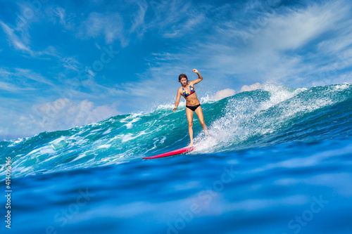 Female surfer on a blue wave at sunny day