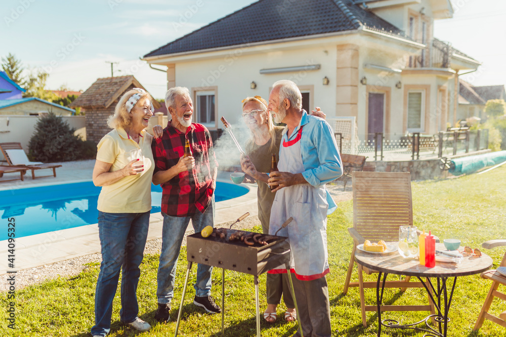 Obraz premium Senior friends having fun at backyard barbecue party