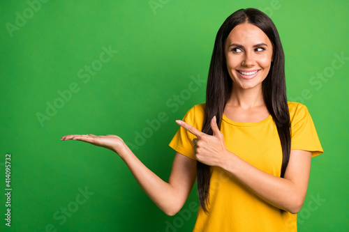 Photo of young girl happy smile dream look point finger empty space ad promo choice choose isolated over green color background