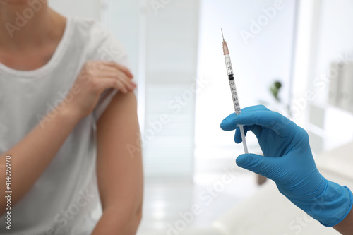 Doctor giving injection to woman in hospital, closeup. Immunization concept