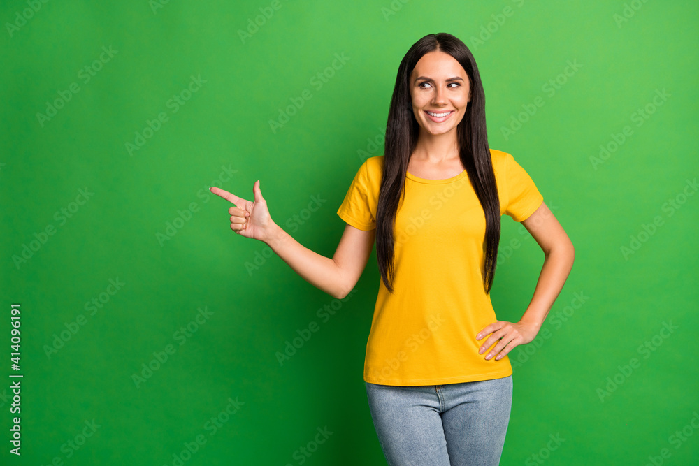 Photo of young girl happy smile dreamy look point finger empty space recommend suggest choice isolated over green color background