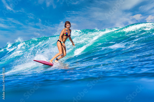 Female surfer on a blue wave at sunny day © trubavink