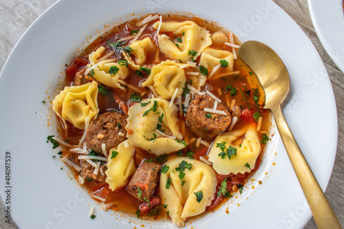 Photography bowl of tortellini soup with Italian sausage flat lay
