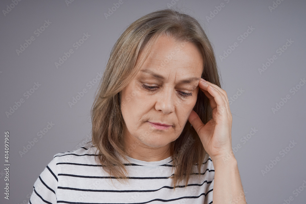 Close up portrait of middle aged woman suffering from headache. Studio shot over gray background. Close up portrait of middle aged woman suffering from headache. Studio shot over gray background.