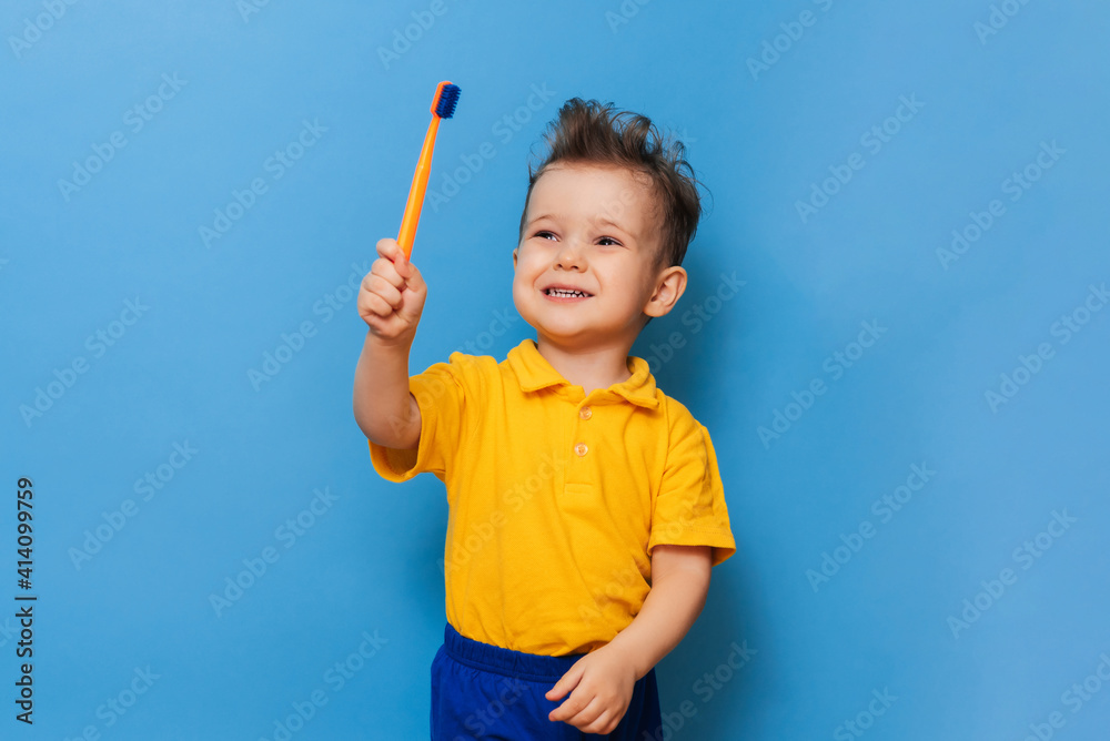 Happy child kid boy brushing teeth with toothbrush on blue background. Health care, dental hygiene. Mockup