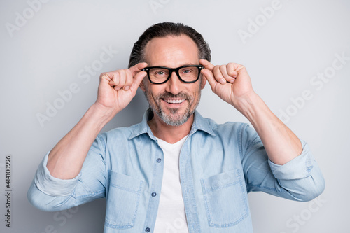 Photo of mature handsome man happy positive smile hands touch eyeglasses isolated over grey color background