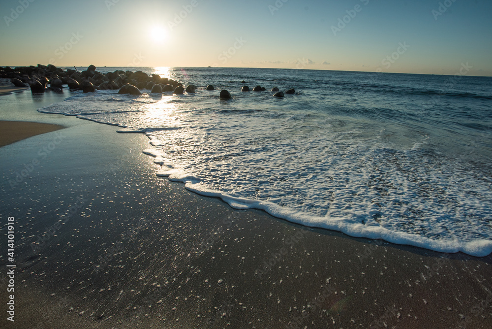 朝日が照らす海の波打ち際