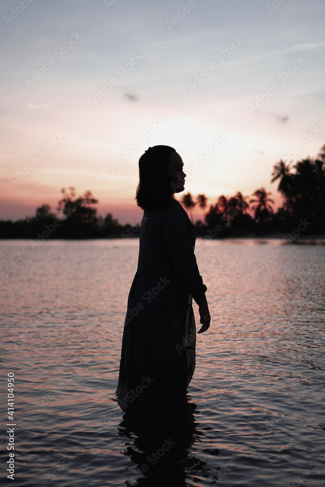 Fototapeta premium Alone woman standing in silhouette on the beach