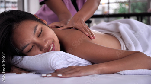 The massage therapist massaging on the back of young Asian woman with aroma essential oil skincare at spa salon.