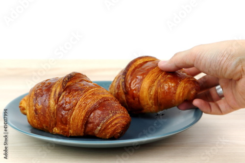 homemade baked butter French croissant serve in blue dish on the wooden table in the cafe for breakfast in the morning