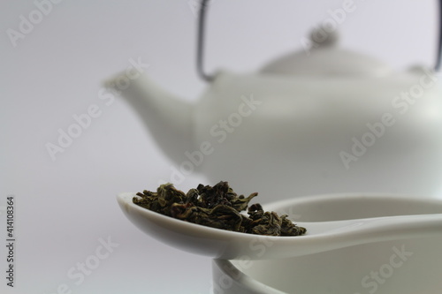 grüner Tee mit weißer asiatischer Teekanne im Hintergrund 