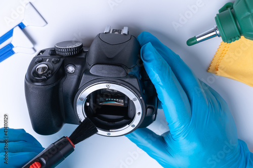 The master cleans the matrix of the DSLR camera with a special brush. Camera cleaning tool