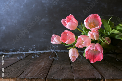 Atmospheric mothers day still life with pink tulips on dark vintage background. Space for text.