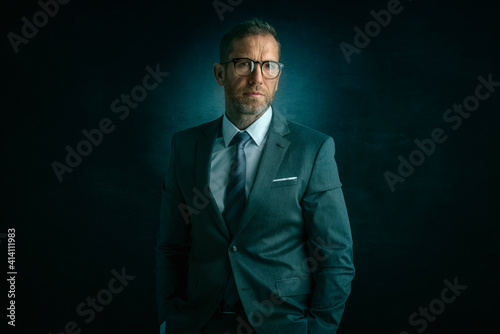 Portrait of senior businessman standing at isolated dark background
