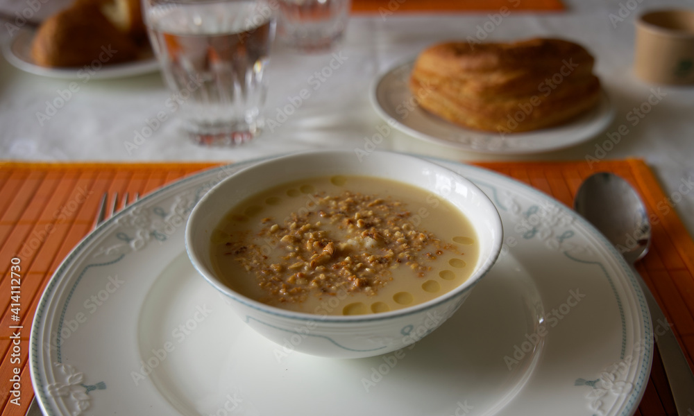 Delicious bowl of gourmet soup on a plate an a table Delicious bowl of gourmet soup on a plate an a table