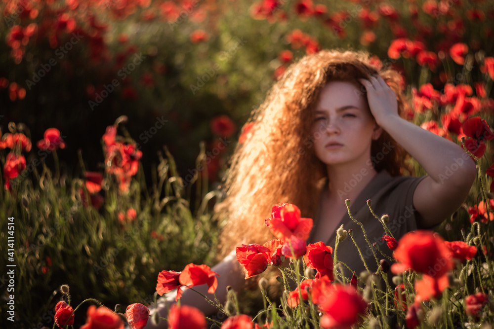 Naklejka premium Young beautiful red-hear girl in red poppy field