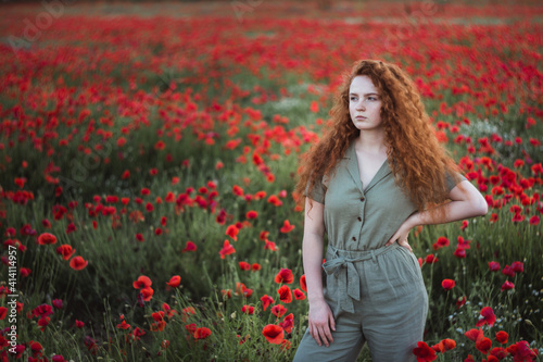 Young beautiful red-hear girl in red poppy field