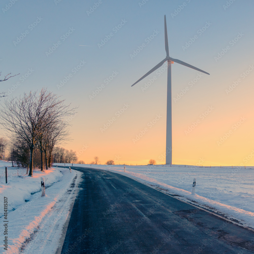 wind turbine and road in winter at sunset