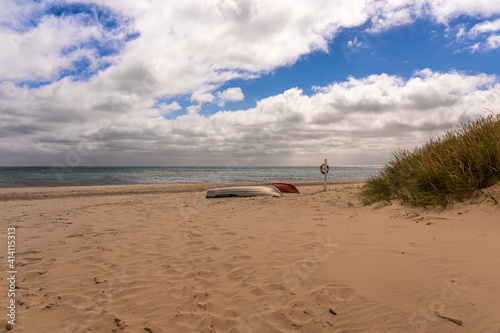Fishing boat lies on the beach in front of the Baltic Sea in the sunset