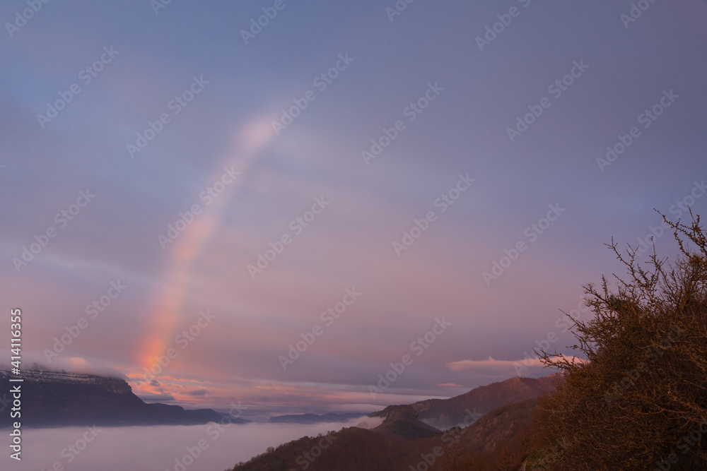 Rainbow in a sunrise with low fog
