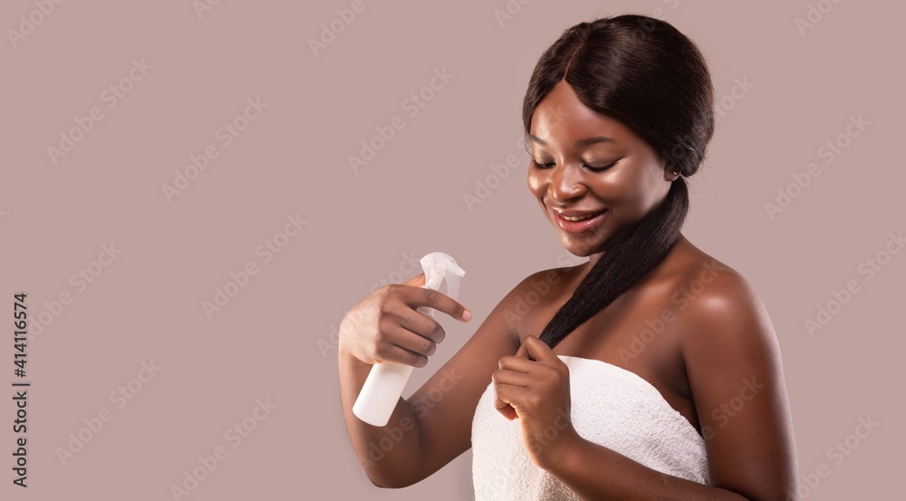 Smiling Black Lady Applying Moisturising Hair Spray, Making Split Ends Repair Treatment Smiling Black Lady Applying Moisturising Hair Spray, Making Split Ends Repair Treatment
