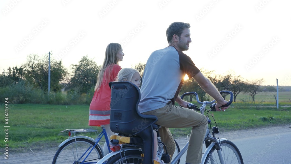 Young couple on a bike with their little daughter at sunset. Young couple on a bike with their little daughter at sunset.