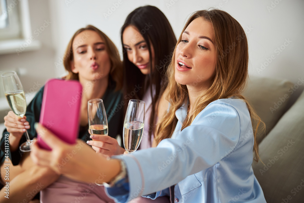 Three relaxed women with champagne flutes posing for the camera Three relaxed women with champagne flutes posing for the camera