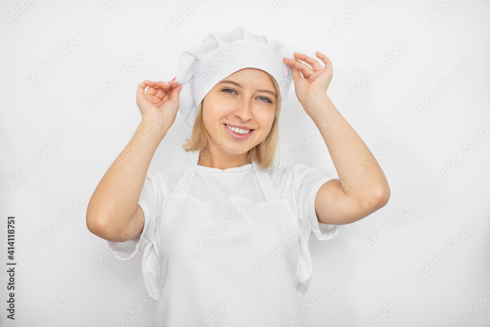 Close up horizontal studio shot of young attractive female pastry chef, wearing white uniform, har and apron, posing to camera on white background with smile Close up horizontal studio shot of young attractive female pastry chef, wearing white uniform, har and apron, posing to camera on white background with smile