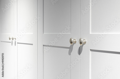 Furniture fittings. Metallic silver door handles with sharp shadows on the white facade