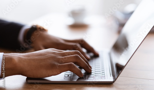 Male hands typing on laptop keyboard, cropped