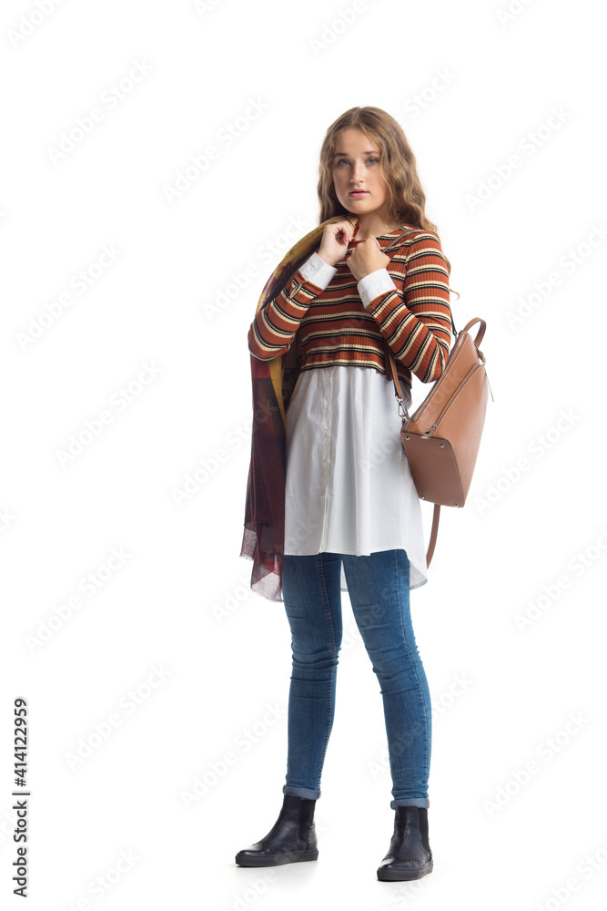 Full length portrait of beautiful stylish girl in fashion blue jeans and striped jumper with long curly hair posing - isolated on white. Fashion model posing at studio. leather backpack in hand Full length portrait of beautiful stylish girl in fashion blue jeans and striped jumper with long curly hair posing - isolated on white. Fashion model posing at studio. leather backpack in hand