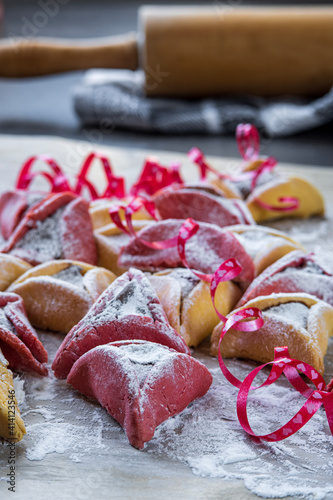 Selective focus on colorful hamantaschen cookies with sugar powder. Jewish traditional pastry for Purim (Jewish carnival holiday). Homemade gluten free cookie filled with chocolate