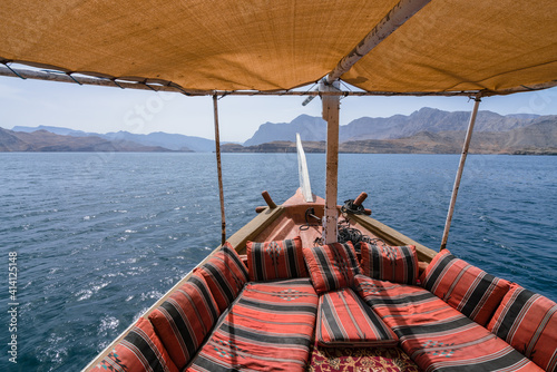 View fom the traditional arabian dhow boat sailing on the sea. Red pillows and carpets, yellow fabric shade. photo