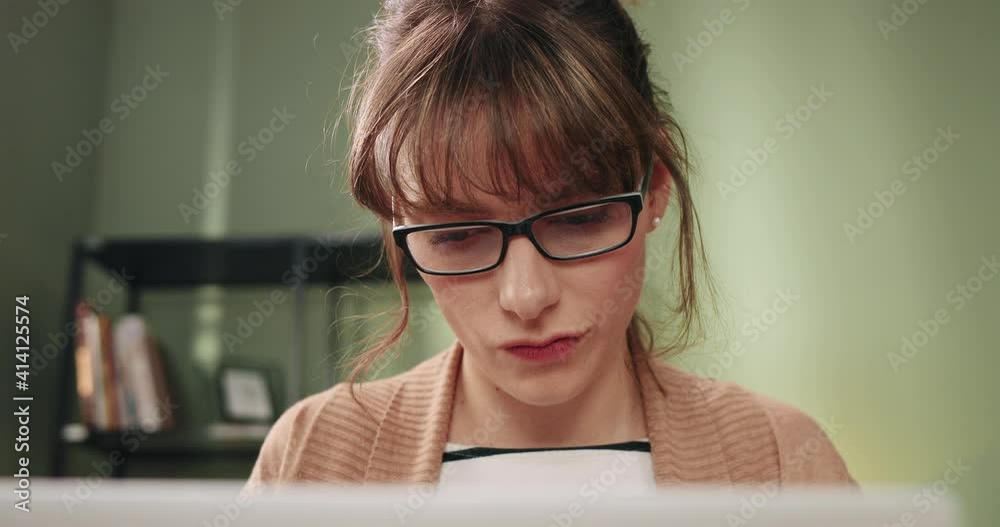 Close up portrait of beautiful woman with glasses sitting at home at desk and working intently at computer. Close up portrait of beautiful woman with glasses sitting at home at desk and working intently at computer.