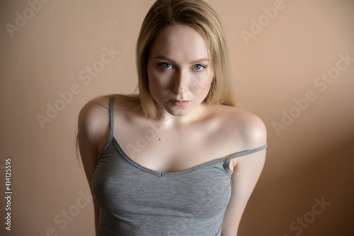 Graceful young woman posing against beige wall.