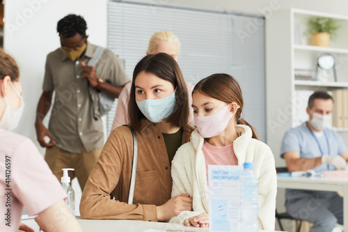 Portrait of mother and daughter wearing masks while registering for covid vaccine at medical center  copy space