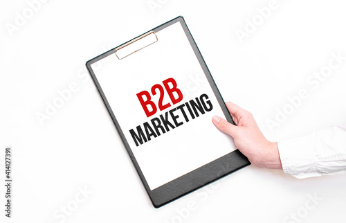 A businessman holds a folder with paper sheet with the text B2B Marketing. Business concept.